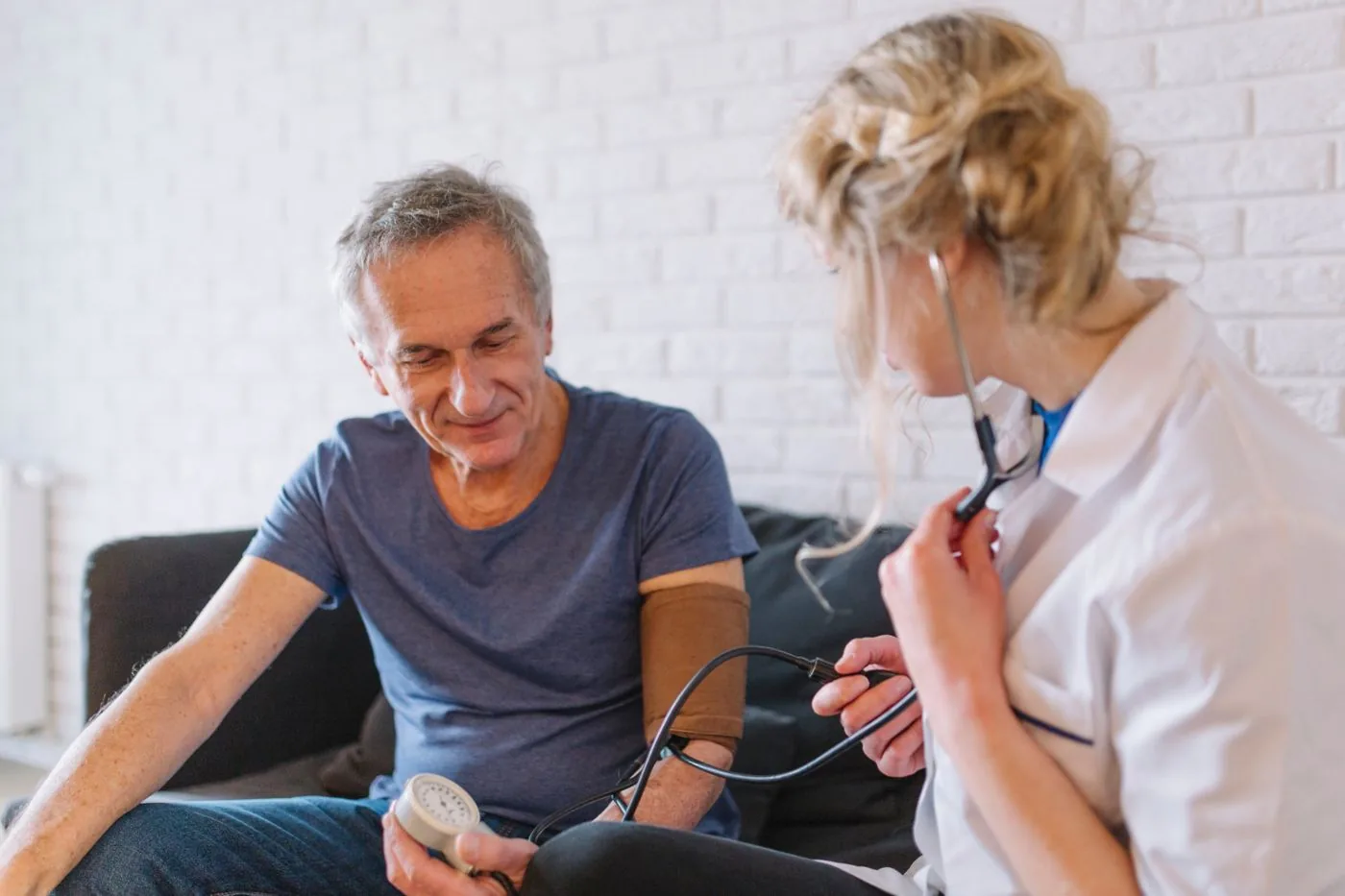Clinician checking an older man’s blood pressure at home